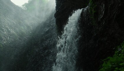 waterfall and man waterfall in the mountains stormy stream of water with drops and splashes powerful stream of a waterfall from a high cliff