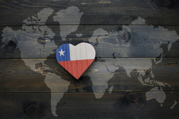 wooden heart with national flag of chile near world map on the wooden background.