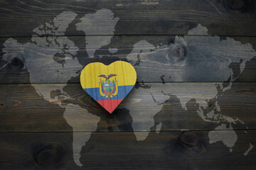 wooden heart with national flag of ecuador near world map on the wooden background.