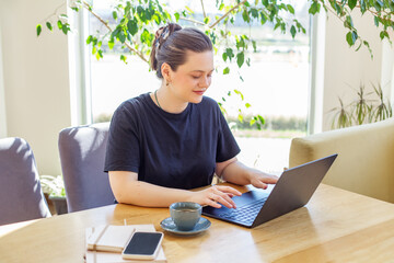Content Woman Working on Laptop with Coffee in Cafe