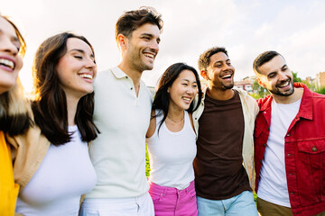 Young group of happy people laughing together outdoors. Diverse student friends having fun standing at college campus. Friendship lifestyle concept
