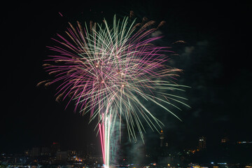 Beautiful golden fireworks sparks celebration festival display night over city background. Celebration festival anniversary bright colorful firework effects star glow on sky dark night party season.