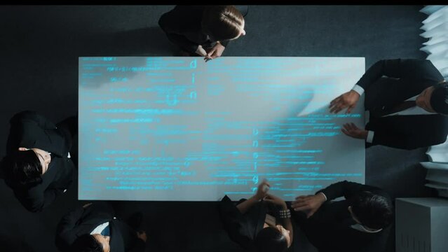 Top down aerial of smart diverse business people discuss about coding engineering prompt. Group of investors brainstorm idea with hologram of software script code or programing code. Directorate.