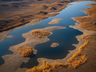 Aerial view reveals river gracefully winding its way through vast landscape. Rivers waters mirror clear sky above.