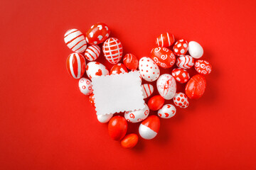 Easter backgrounds, a heart of Easter red and white eggs on a red background. Copy space. Flat lay, top view. Easter love. Valentine's day