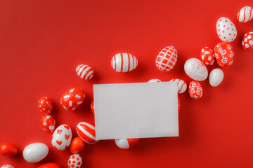 Easter banner with a blank sheet of paper and Easter red and white eggs on a bright red background. Copy space. Flat lay, top view