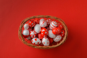 Easter backgrounds with a basket of red and white Easter eggs on a bright red background. A place to copy. Flat image, top view