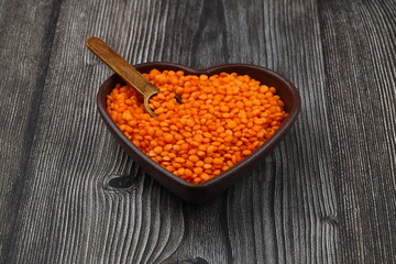 Pile red lentil in shape of heart isolated on wooden background. Top view. Flat lay. Vegetarian and vegan diet. High content of B vitamins in Red lentils. healthy Superfood