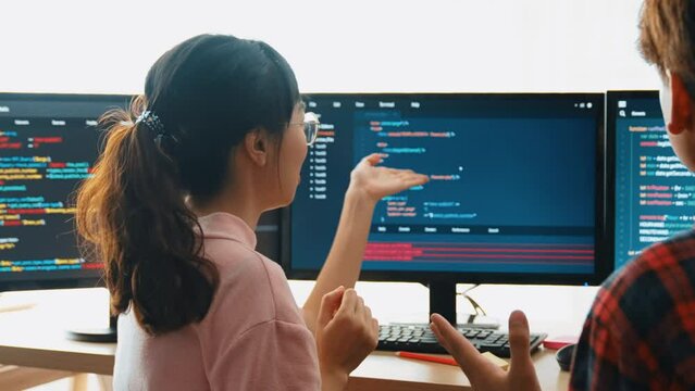 Slow motion back end software developer engineer for computer programming working together on debugging writing computing code, solving complex algorithms display on monitor in office. Burgeoning