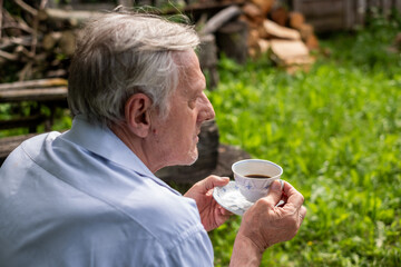 Man in profile holding a teacup, gazing into the distance in a lush garden a moment of quiet reflection, and elderly peace.