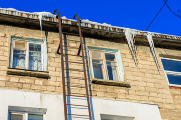 Large icicles on the roof pose a danger to passersby. Background with selective focus and copy space