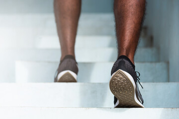 Close up athlete shoes of legs young sport runner black man step running up to climbing stairs...