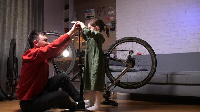 dad and daughter pumping up a bicycle wheel together with a hand pump - Powered by Adobe