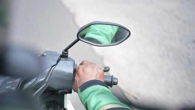 Video taken by an online motorcycle taxi passenger crossing the streets of Jakarta during the day, focusing on the driver's right hand and steering wheel