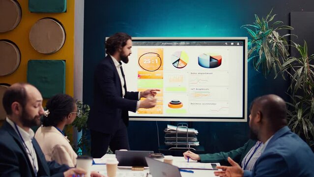 Financial analyst briefing his team about new company objectives, making budget and sales presentation with interactive board. Specialist addressing resource allocation and project planning. Camera B.