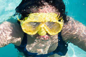 Girl with googles in swimming pool underwater in hot sunny day - obrazy, fototapety, plakaty