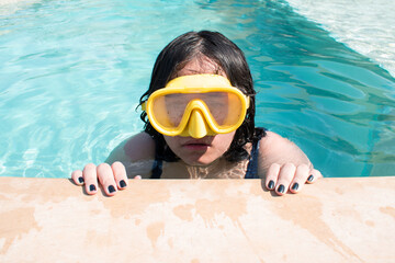 Girl with googles in swimming pool edge in hot sunny day	