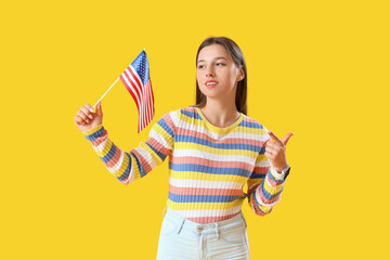 Beautiful young woman with USA flag on yellow background