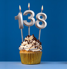 Burning candle number 138 - Birthday card with cupcake on blue Background - obrazy, fototapety, plakaty