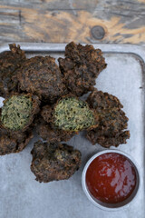 American food. Top view of spinach fritters with spicy barbecue sauce in a metal plate	
