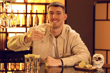 Young man with tequila shot in bar at night