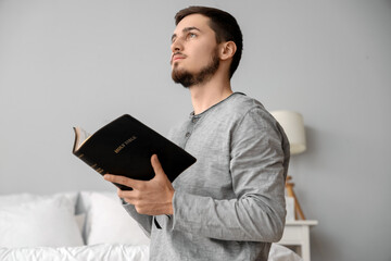 Young man reading Bible in bedroom