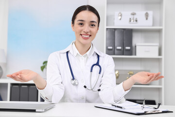 Medical consultant with stethoscope at table in clinic