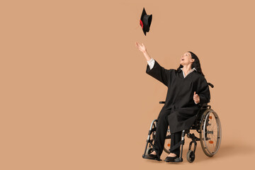Beautiful female graduate student in wheelchair with graduation cap on brown background