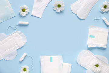 Menstrual pads with chrysanthemum flowers and tampons on blue background