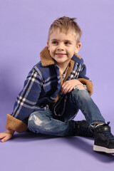 Fashion concept. Stylish boy posing on violet background