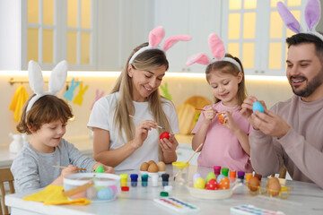 Easter celebration. Happy family with bunny ears painting eggs at white marble table in kitchen