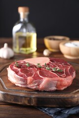 Piece of raw beef meat and thyme on wooden table, closeup