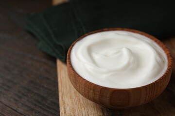Delicious natural yogurt in bowl on wooden table, closeup. Space for text
