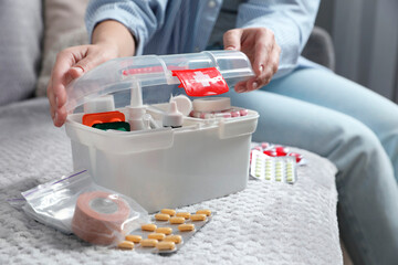 Woman opening first aid kit indoors, closeup