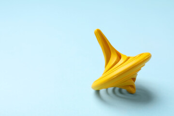 One yellow spinning top on light blue background, closeup