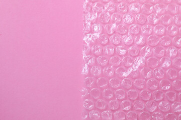 Transparent bubble wrap on pink background, top view. Space for text