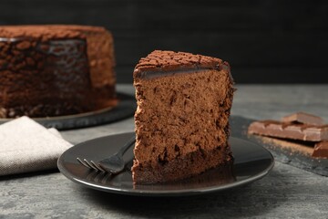 Piece of delicious chocolate truffle cake and fork on grey textured table, closeup