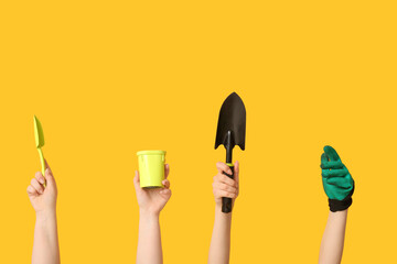 Female hands with gardening tools on yellow background