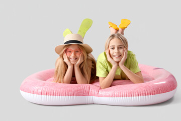 Cute little kids lying on inflatable mattress in shape of heart against grey background