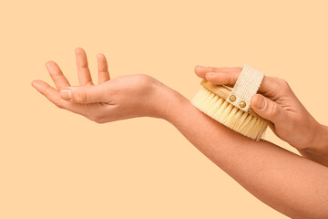 Female hands with body massage brush on beige background