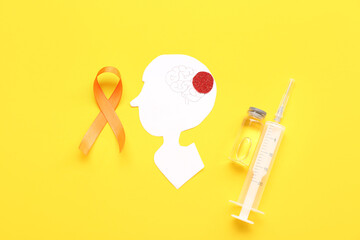 Paper human head with syringe and orange ribbon on yellow background. Multiple Sclerosis Awareness...