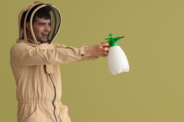 Male beekeeper with sprayer on green background