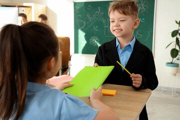 Cute little pupils with copybook in classroom. School holidays concept