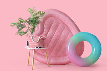 Swimming mattress in shape of heart, inflatable ring and bag on stool on pink background