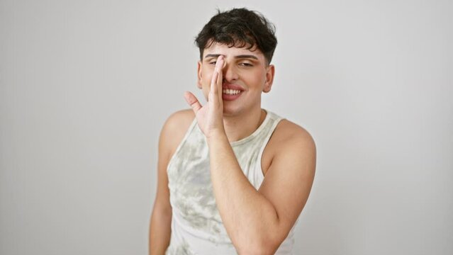 Gossiping young man, spotted whispering secrets! wearing sleeveless t-shirt, standing isolated on white background. expression of mystery, mouth covered by hand. reviving lgbtq conversation.