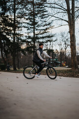 A young male teen cyclist takes a leisurely ride through a tranquil park as evening falls.