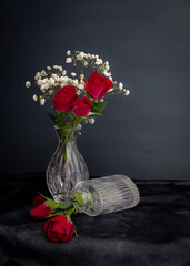 Red tea roses in petite vase, close-up.