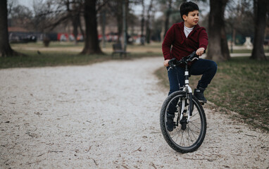 A joyful young boy riding his bicycle outdoors in the park, portraying activity and childhood joy.