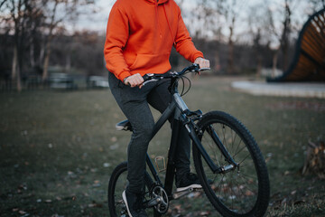 Active young man with a bicycle spending his free time or weekend in an urban park, embodying a...