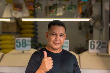 A happy owner of a rice trading business. A rice retailer making a thumbs up sign.